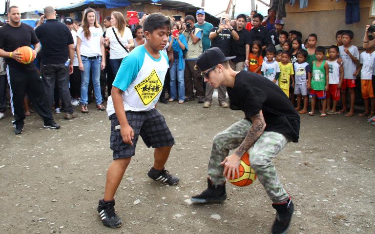 Justin Bieber (right) plays basketball with a young survivor of Super Typhoon Haiyan in Palo, Leyte province on December 10, 2013