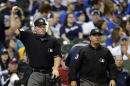 Umpire Ted Barrett, left, signals an out call after listening to the central replay booth in New York in the sixth inning of an opening day baseball game between the Atlanta Braves and Milwaukee Brewers, Monday, March 31, 2014, in Milwaukee. An umpire's call has been overturned for the first time under Major League Baseball's expanded replay system, with Brewers' Ryan Braun ruled out instead of safe. (AP Photo/Jeffrey Phelps)