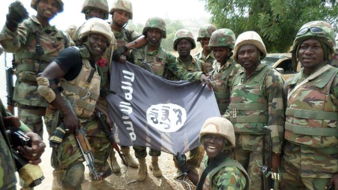 Handout picture from the Nigerian military taken on February 26, 2015 shows troops posing with a flag of Boko Haram after dismantling a Boko Haram camp along Djimitillo Damaturu road, Yobe State in northeastern Nigeria, following fierce fighting