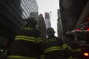 Firefighters look up at a partially collapsed crane hanging from a high-rise building in Manhattan as Hurricane Sandy makes its approach in New York