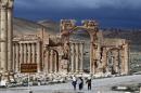 A picture taken on March 14, 2014 shows visitors walking near the famous Arch of Triumph of the ancient oasis city of Palmyra. Islamic State extremists have blown up the famous arch and other monuments at the UNESCO World Heritage Site