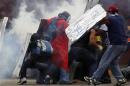 Anti-government protesters shield themselves from tear gas during a rally in Caracas