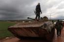 A Syrian rebel fighter stands on a tank near the frontline in the village of Ratyan, north of Aleppo on February 19, 2015