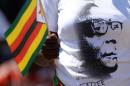A Zimbabwean woman, wearing a T-shirt bearing a portrait of Robert Mugabe, waves a national flag as she greets President Robert Mugabe during his swearing-in ceremony on August 22, 2013 at the 60,000-seater sports stadium in Harare