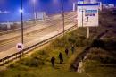 Migrants walk along a highway towards the Eurotunnel site in Coquelles, northern France, on October 3, 2015