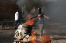 A protester gestures in front of a burning barricade in Bujumbura