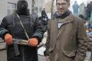 In this photo taken on Sunday, April 13, 2014, a reporter Simon Ostrovsky, right, stands next to a Pro-Russian gunman at a seized police station in the eastern Ukraine town of Slovyansk. Pro-Russian gunmen in eastern Ukraine say they are holding an American journalist captive. Ostrovsky, a journalist for Vice News, has not been seen since early Tuesday. (AP Photo/Efrem Lukatsky)