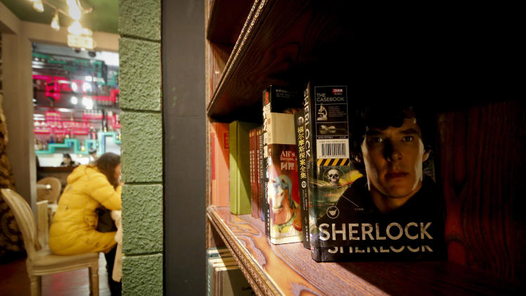 In this photo taken on Friday, Jan. 17, 2014, a girl has a drink near books shelf displaying Sherlock Holmes books at a "Sherlock"-themed cafe in Shanghai, China. "Sherlock’’ has become a global phenomenon, but nowhere more than in China, where fans’ devotion is so intense that the BBC says this was the first country outside Britain where the new season was shown. (AP Photo)