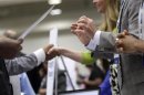 Corporate recruiters gesture and shake hands as they talk with job seekers at a Hire Our Heroes job fair targeting unemployed military veterans and sponsored by the Cable Show, a cable television industry trade show in Washington