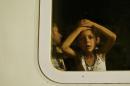 A migrant child looks out of a train window at a train station in Tovarnik