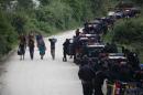 People walk next to a police convoy patrolling a village in San Juan Sacatepequez, Guatemala, Monday, Sept. 22, 2014. Guatemalan authorities have suspended some constitutional rights in San Juan Sacatepequez where 11 villagers died in a battle with guns and machetes on Friday night. The clash took place in the village of Pajoques between residents who support plans to build a cement factory and highway, and others who fear the construction could hurt their lands. (AP Photo/Moises Castillo)