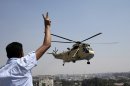 A man flashes a victory sign at an Egyptian military helicopter as it flies over the presidential palace in Cairo, Egypt, Friday, July 26, 2013. Political allies of Egypt's military lined up behind its call for huge rallies Friday to show support for the country's top general, Abdel-Fattah el-Sissi, pushing toward a collision with Islamist opponents demanding the return of Mohammed Morsi, the nation's ousted president. (AP Photo/Hassan Ammar)