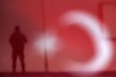A soldier is seen through a Turkish national flag as he stands guard during an AK Party election rally in Diyarbakir