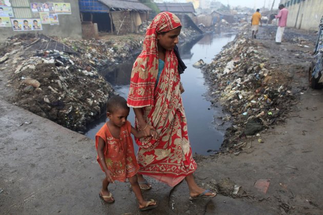 A woman and crosses a bridge with her child next to a tannery factory by the river Buriganga at Hazaribagh in Dhaka.