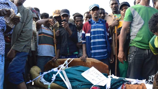 People in Wolenkomi, some 60km west of Ethiopia&#39;s capital Addis Ababa stand on December 15, 2015 near the body of a protester from Ethiopia&#39;s Oromo group allegedly shot dead by security forces