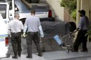 Miami-Dade morgue workers carry out a body out at the scene of a fatal shooting in Hialeah, Fla., Saturday, July 27, 2013. A gunman holding hostages inside the apartment complex killed six people before being shot to death by a SWAT team that stormed the building early Saturday following an hours-long standoff, police said. (AP Photo/Alan Diaz)
