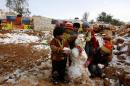 Young Syrian refugees build a snowman following a storm in a makeshift refugee camp in the Lebanese village of Baaloul in the Bekaa Valley, on December 12, 2013