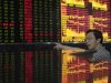 An investor gestures as he talks in front of an electronic board showing stock information at a brokerage house in Wuhan, Hubei province