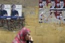 A woman walks past election campaign posters of presidential candidates, Mohamed Mursi and Ahmed Shafiq, in Cairo