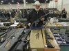 FILE - In this Jan. 6, 2013 file photo, Ken Haiterman, of Pioneer Market, holds a CMMG 5.56mm AR 15 during the 2013 Rocky Mountain Gun Show in Sandy, Utah. A bipartisan quartet of senators, including two National Rifle Association members and two with “F” ratings from the potent firearms lobby, are quietly trying to reach compromise on expanding the requirement for gun-sale background checks. (AP Photo/Rick Bowmer, File)