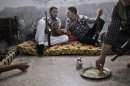 A Syrian rebel fighter, right, eats while others chat as they wait for transportation to go and fight government forces in Aleppo, at their headquarters in Suran, on the outskirts of Aleppo, Syria, Monday, Sept. 10, 2012. (AP Photo/Muhammed Muheisen)