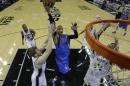 Dallas Mavericks' Monta Ellis (11) drives to the basket between San Antonio Spurs' Matt Bonner, left, and Tim Duncan, right, during the first quarter of Game 1 of the opening-round NBA basketball playoff series, Sunday, April 20, 2014, in San Antonio. (AP Photo/Eric Gay)