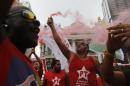 Demonstrators wearing Workers Party t-shirts hold flares and shout slogans during a protest in support of the state-run oil company Petrobras in Rio de Janeiro, Brazil, Friday, March 13, 2015. Brazilian unions and backers of President Dilma Rousseff marched Friday in several cities across the nation, mostly to show support for state-run oil company Petrobras as it's engulfed by a corruption scandal, but also to back Rousseff. (AP Photo/Leo Correa)