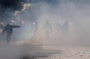 Protesters throw stones amidst smoke during clashes with riot police near the Interior Ministry in Tunis