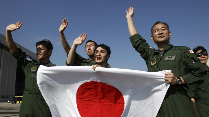 Ground crew members hold a Japanese flag as they wave to a Japan Maritime Self-Defense Force&#39;s P3C patrol plane as it leaves the Royal Malaysian Air Force base for Australia to join a search and rescue operation for the missing Malaysia Airlines, flight MH370, in Subang, Malaysia, Sunday, March 23, 2014. Search planes headed back out to a desolate patch of the southern Indian Ocean on Sunday in hopes of finding answers to the fate of the missing Malaysia Airlines jet, after China released a satellite image showing a large object floating in the search zone. (AP Photo/Lai Seng Sin)