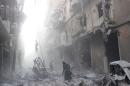 A Syrian woman makes her way through debris following an air strike by government forces in the northern city of Aleppo on July 15, 2014