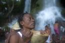 A voodoo pilgrim prays before bathing in a waterfall believed to have purifying powers during the annual celebration in Saut d' Eau, Haiti, Wednesday, July 16, 2014. The annual pilgrimage is made in honor of Haiti's most celebrated patron saint, Our Lady of Mount Carmel who according to legend appeared on a palm tree in 1847 in the Palm Grove in Saut d'Eau and was integrated into Haiti's voodoo culture as the goddess of love. (AP Photo/Dieu Nalio Chery)