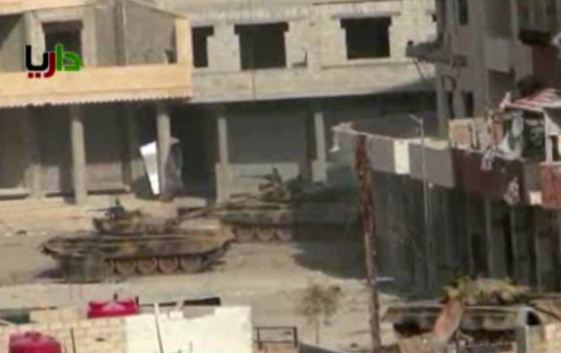 In this image taken from video obtained from the Sham News Network, which has been authenticated based on its contents and other AP reporting, a pair of what activists say are tanks from President Bashar Assad regime in sit in a street in the Daraya neighborhood of Damascus, Syria, just before one of them fires a shot Friday, Jan. 25, 2013. Troops battled rebels around Damascus in an effort to dislodge opposition fighters who have set up enclaves around the capital, including Daraya and Zabadani. (AP Photo/Sham News Network via AP video)