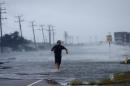 A man crosses a flooded Highway 64 as wind pushes water over the road as Hurricane Arthur passes through Nags Head, N.C., Friday, July 4, 2014. (AP Photo/Gerry Broome)