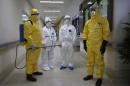 Health workers in protection suits wait in the corridor near a quarantine ward during a drill to demonstrate the procedures of handling Ebola victims, at a hospital in Guangzhou