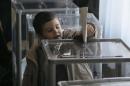 A boy drops ballot sheets into a ballot box at a polling station during parliamentary elections in Kiev, Ukraine, Sunday, Oct. 26, 2014. Voters in Ukraine headed to the polls Sunday to elect a new parliament, overhauling a legislature tainted by its association with ousted President Viktor Yanukovych. (AP Photo/Efrem Lukatsky