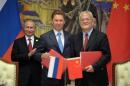 Russia's President Vladimir Putin, left, applauds, during signing ceremony in Shanghai, China on Wednesday, May 21, 2014 while Russian Gazprom CEO Alexei Miller, second left, and China's CNPC head Zhou Jiping, second right, hold documents, China's President Xi Jinping, stands partially seen at right. China signed a long-awaited, 30-year deal Wednesday to buy Russian natural gas worth some $400 billion in a financial and diplomatic boost to diplomatically isolated President Vladimir Putin. (AP Photo/RIA Novosti, Alexei Druzhinin, Presidential Press Service)