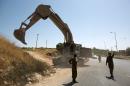 Israeli soldiers stand next to an army bulldozer deployed near Hebron in the occupied West Bank on June 17, 2014