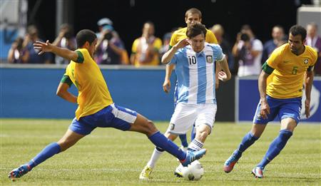 Argentina forward Lionel Messi dribbles between Brazil midfielder Romulo and Sandro during their international friendly soccer match in East Rutherford