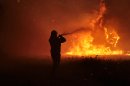 A firefighter works to extinguish a forest fire in Varibobi, a northwestern suburb of Athens, Tuesday, Aug. 6, 2013. A large wildfire raged through the suburb burning about four houses. No injuries were reported. (AP Photo/Michail Michailidis)
