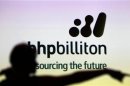 A woman gestures in front of a BHP Billiton sign during a half-year results briefing by the company's Chief Executive Marius Kloppers, in central Sydney