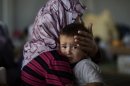 Little Amjad Al-Saleh, whose family fled their home in September, is comforted by his mother after suffering food poisoning.
