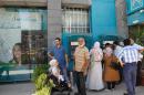 Palestinians living in Damascus wait outside a bank to collect financial aid donated by the United Nations' Palestinian refugee agency UNRWA in the Syrian capital Damascus, on September 17, 2013