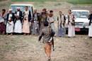 An armed boy walks as he attends a gathering held by tribesmen loyal to the Houthi movement in Sanaa