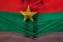A man stand in front of the Burkina Faso nationals flag during a memorial ceremony for the victims of the recent hotel attack where extremist killed foreigners and Burkina Faso nationals, in Ouagadougou, Burkina Faso, Saturday, Jan. 23, 2016. Burials have begun for the 10 Burkina Faso nationals killed in last week's attack on a cafe and hotel in the capital, Ouagadougou, highlighting the local toll suffered in the latest West African country targeted by Islamic extremists. (AP Photo/Theo Renaut)
