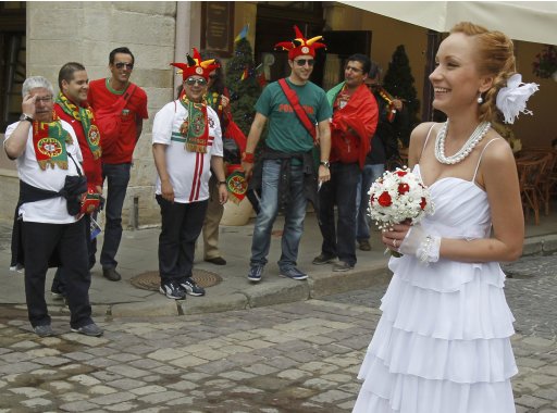 Portuguese soccer fans watch a bride as she pose for photographs in central