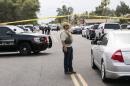 An FBI agent lift police tape at one of the scenes of a multiple location shooting that has injured at least four people in Mesa, Arizona at one of the scenes of a multiple location shooting that has injured at least four people in Mesa, Arizona