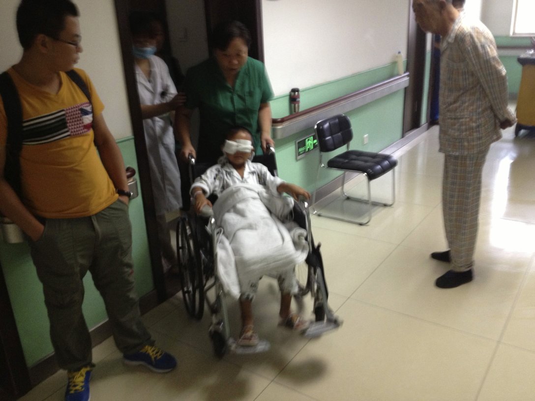 A boy whose eyes were gouged out is pushed in a wheelchair at a hospital in Taiyuan