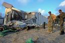 Somali soldiers and resident stand near destroyed buildings on February 27,2016 in Mogadishu, Somalia