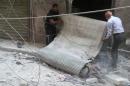 Residents inspect a shop at a site hit by airstrikes, in the rebel-held area of Aleppo's Bustan al-Qasr
