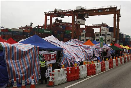 A policeman walks past tents set up by protesting dock workers during a strike outside Kwai Chung container terminal, which is operated by Hong Kong International Terminals Ltd., in Hong Kong April 10, 2013. REUTERS/Bobby Yip